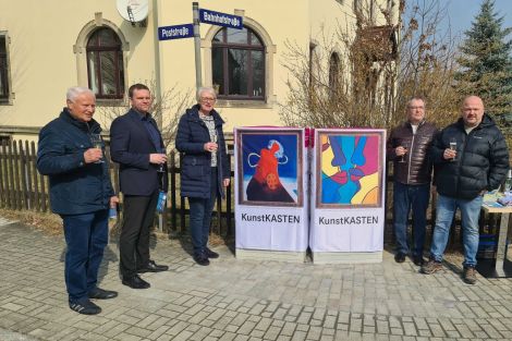 5 Personen zusammen vor 2 zum Kunstkasten verhüllten Netzverteilern an einer Straße in Arnsdorf.