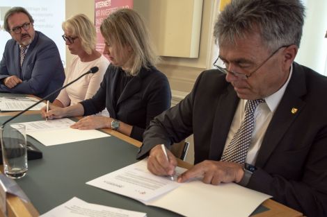 2 Männer und 2 Frauen unterzeichnen Verträge.