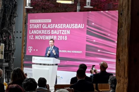 Ministerpräsident Kretzschmar redet auf einem Podest vor einem großen Banner zum Glasfaserausbau.