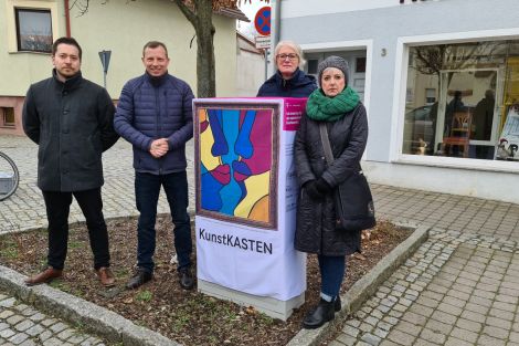 4 Personen zusammen vor einem zum Kunstkasten verhüllten Netzverteiler an einer Straße in Wittichenau.