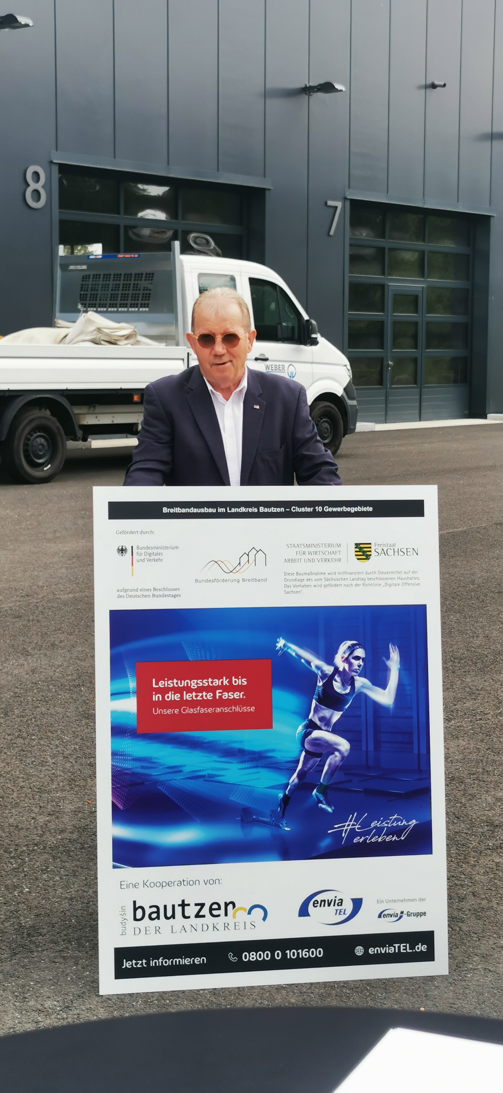 Manfred Heine (Bürgermeister Gemeinde Streetal) steht hinter einer Informationstafel zum Breitbandausbau.